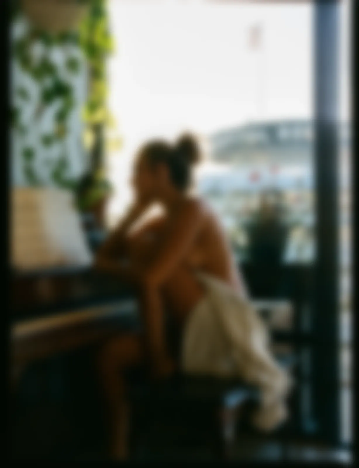 Kvinna insvept i en handduk vid ett piano framför ett ljust fönster.